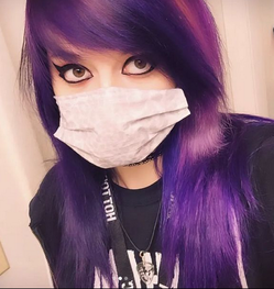 A close up of Trinity Coblentz with purple hair wearing a mask, black eyeliner, Hot Topic lanyard.